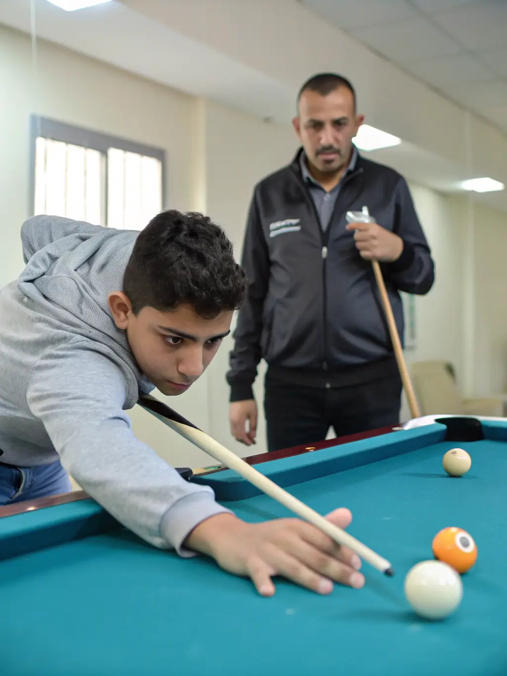 A workshop session focused on advanced billiard techniques, with an experienced coach demonstrating precise shots and strategies to attentive participants.
